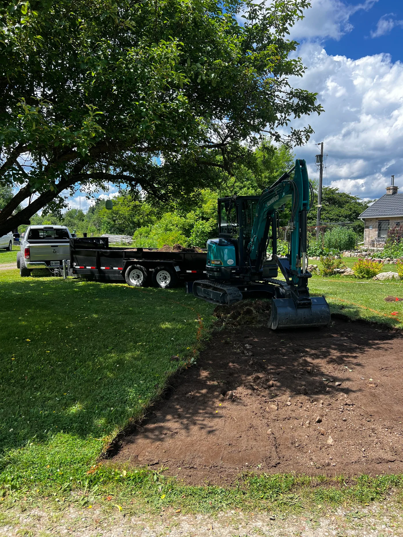 CP Excavating's mini excavator, dump trailer and truck set up for work on a property