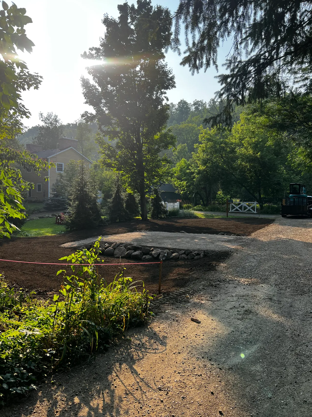 A freshly graded property with a stone-edged island and gravel drive at first light