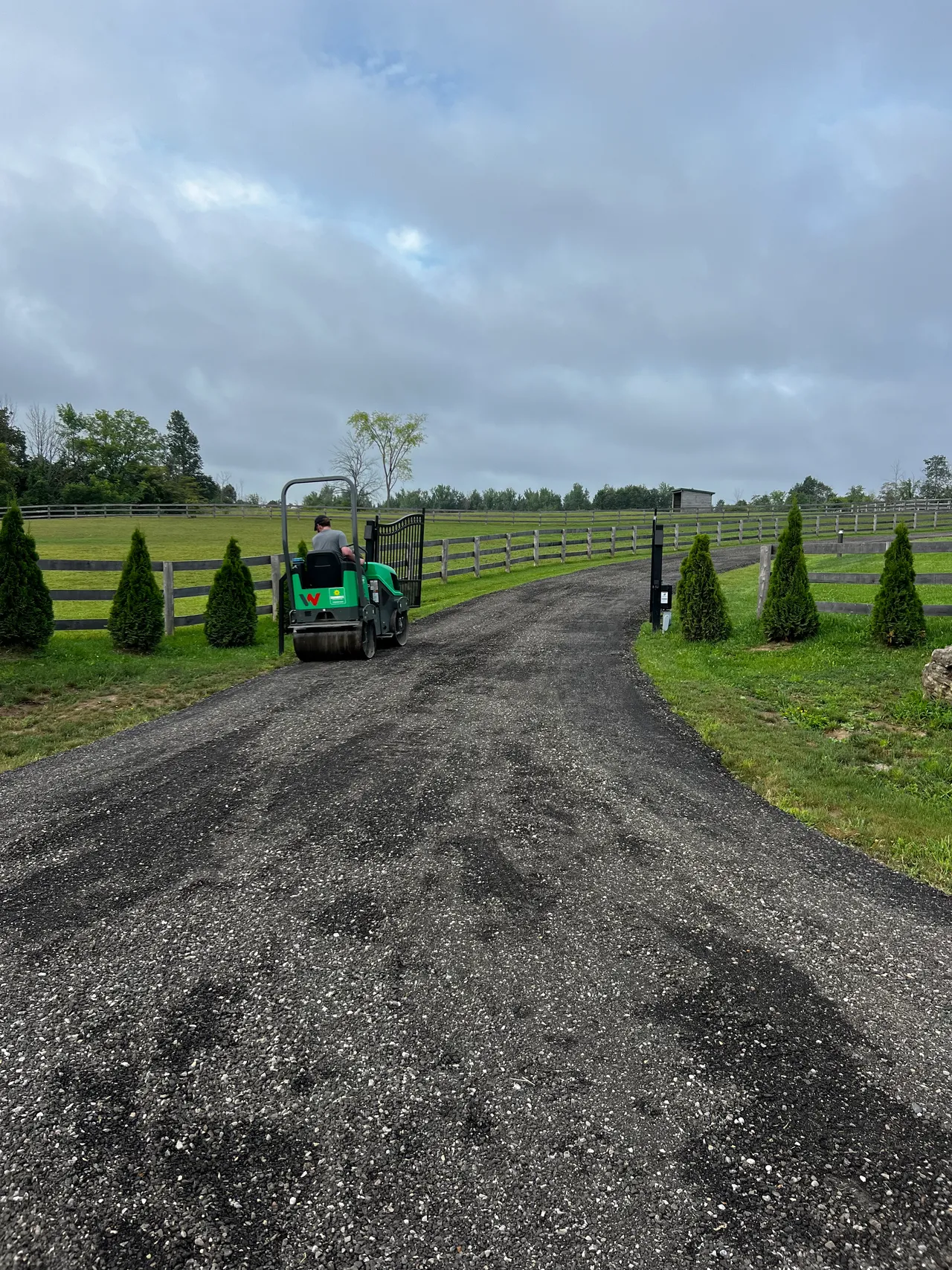 A ride-on roller compacting a fresh laneway through an equestrian property